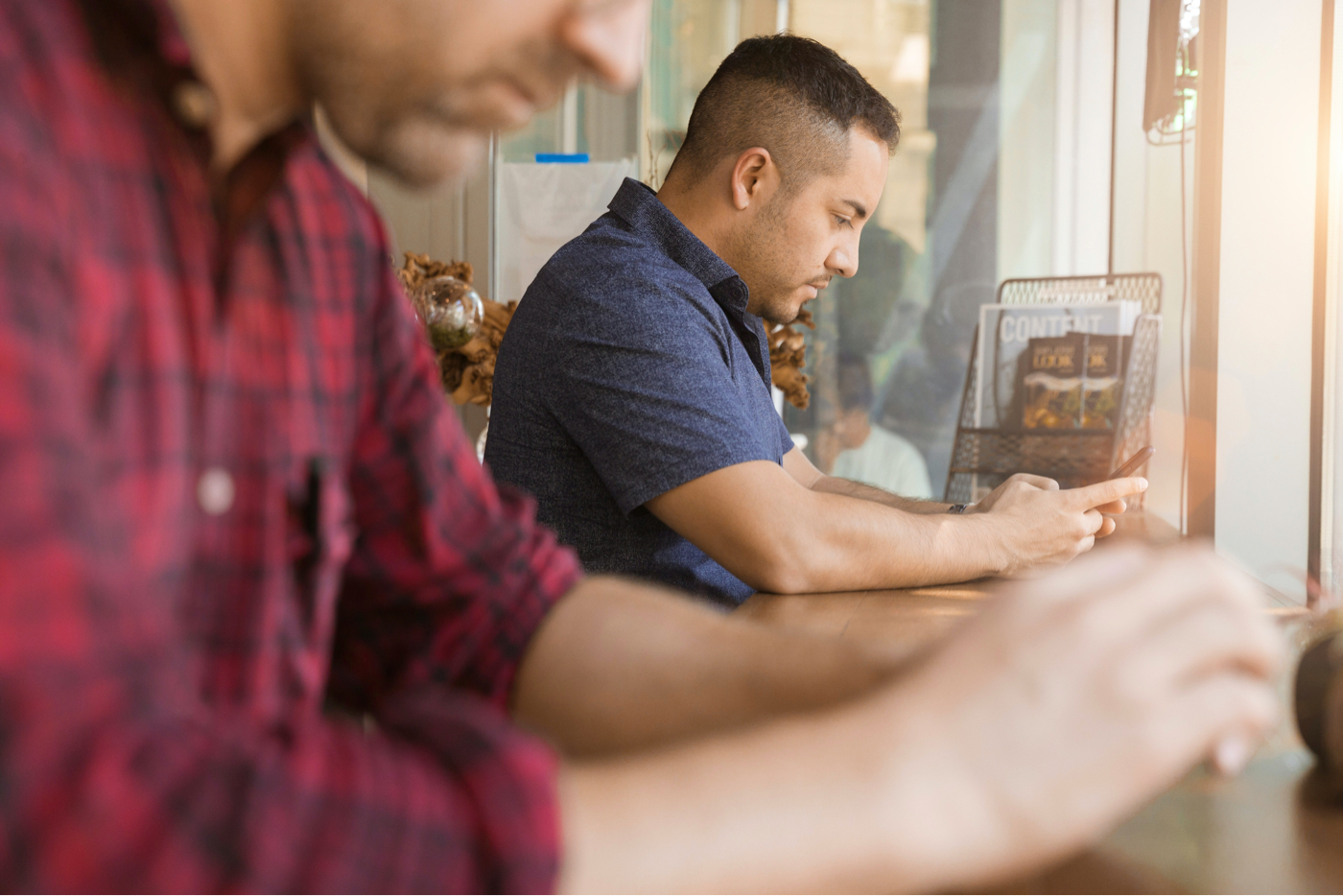 People sitting at a restaurant counter using online banking on their phones.